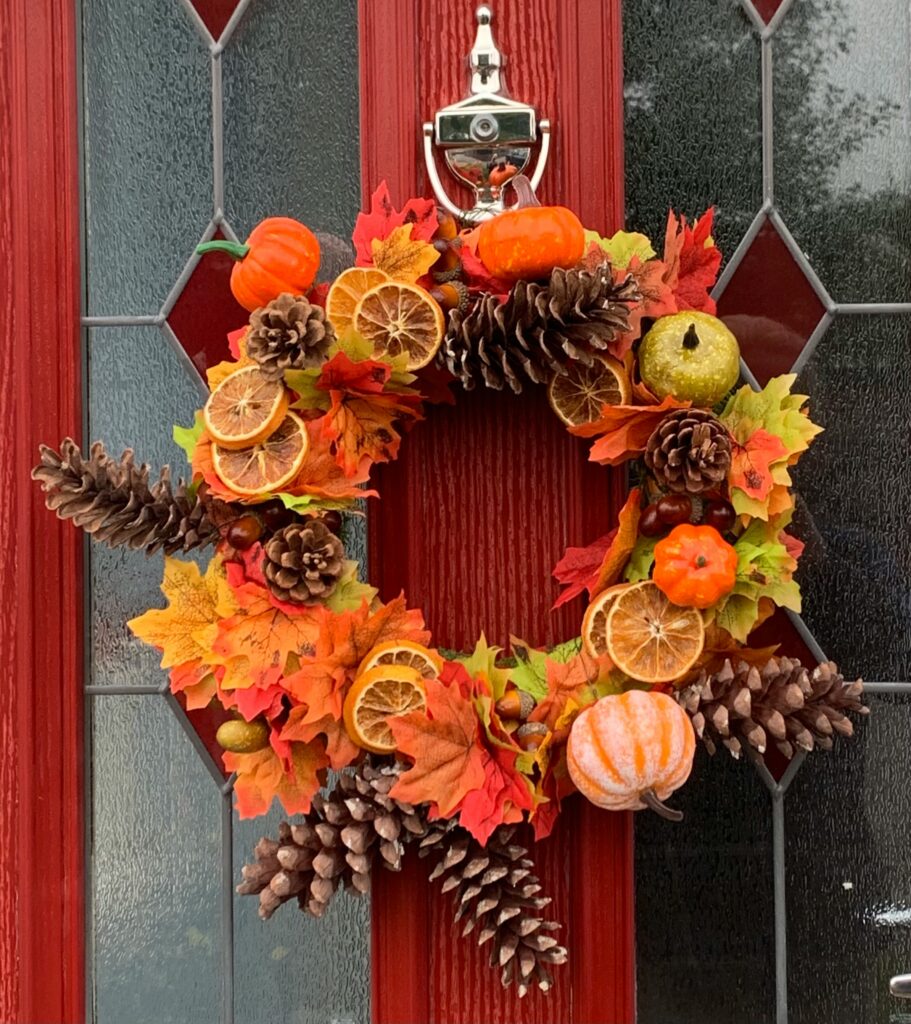 Fall Porch Pumpkin Decor with seasonal wreath on a red door